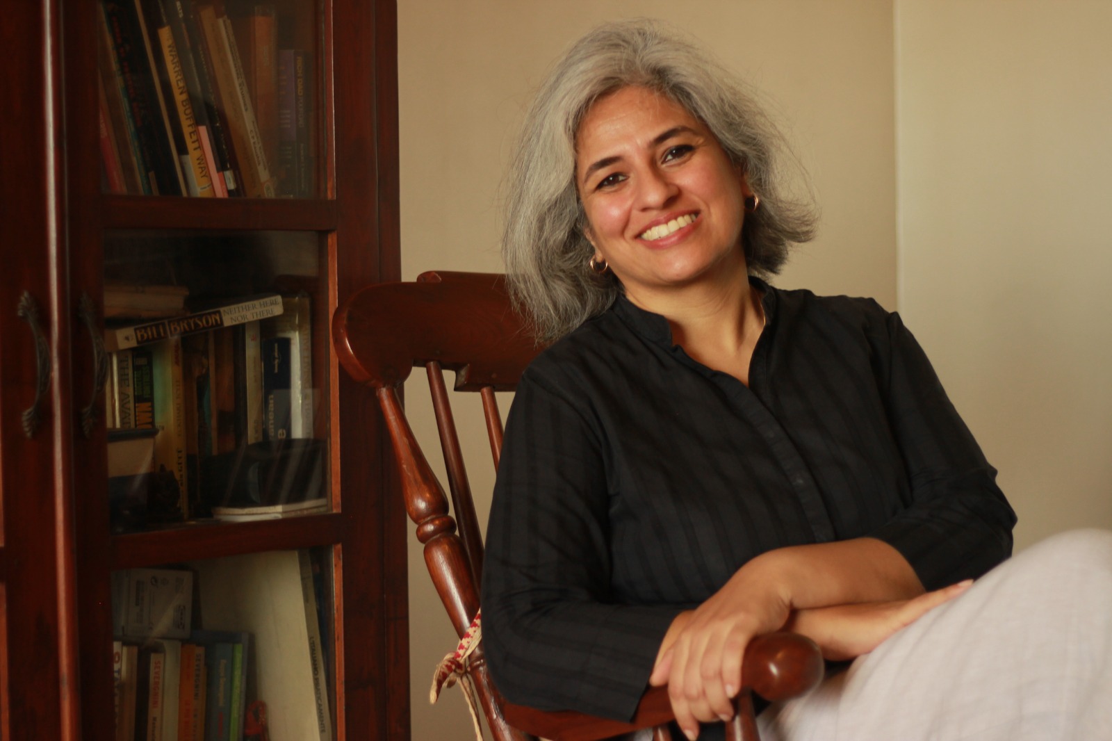 Nina Saxena seated beside a bookshelf